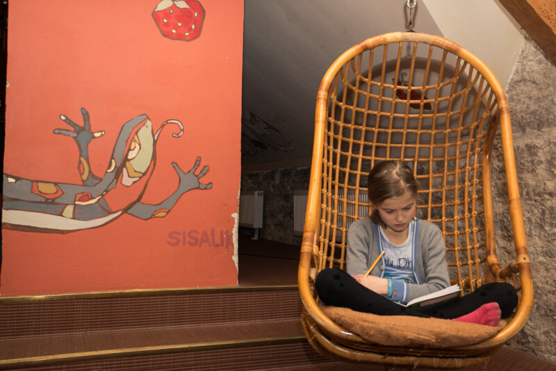 Tüdruk istub toolis ja loeb raamatut pliiats käes