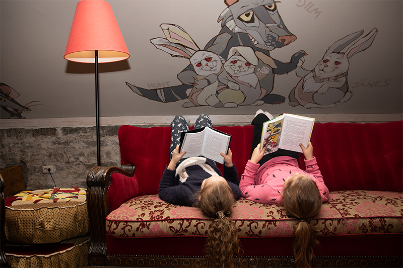 Lapsed lugemas raamatuid keskuse diivanil peaalaspidi