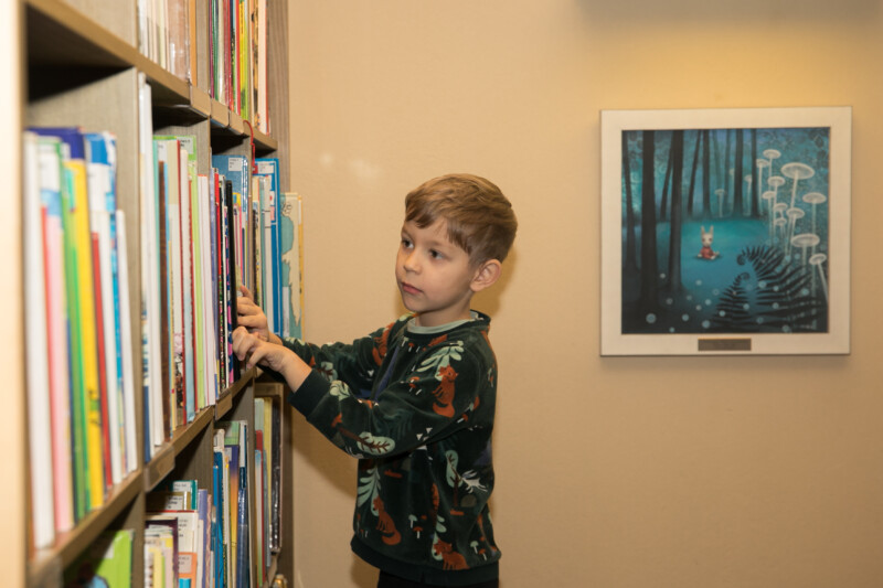 Poiss valib riiulist raamatut.